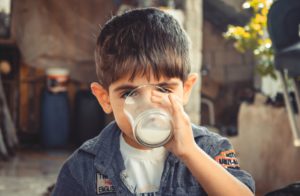la imagen muestra un niño bebiendo un vaso de leche de vaca entera