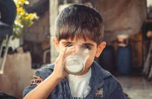la imagen muestra un niño bebiendo un vaso de leche de vaca entera